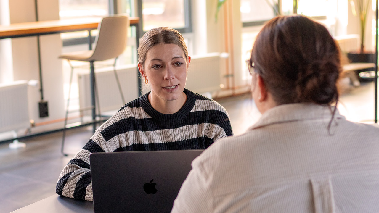 NeueBilder_Überuns_1280px_Teil2_15 zwei Personen im Büro, die sich unterhalten