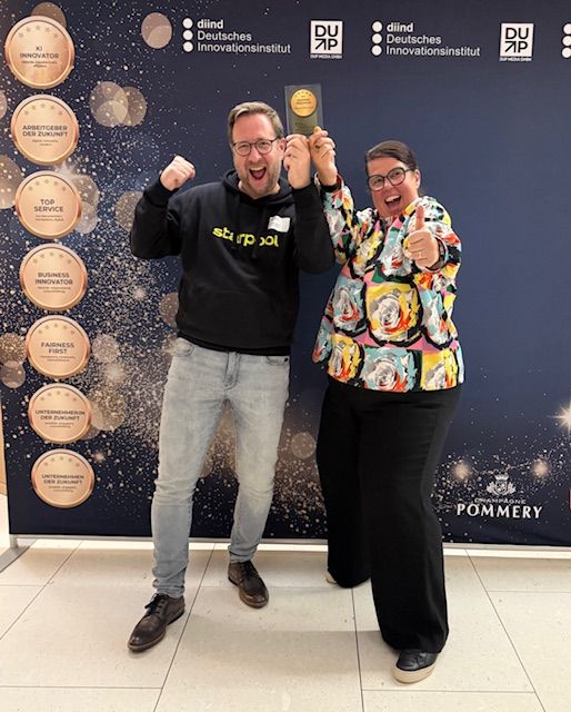 Awardverleihung Bettina Vockel und Christian Niemann auf einer Bühne mit Awards in der Hand nach der Verleihung